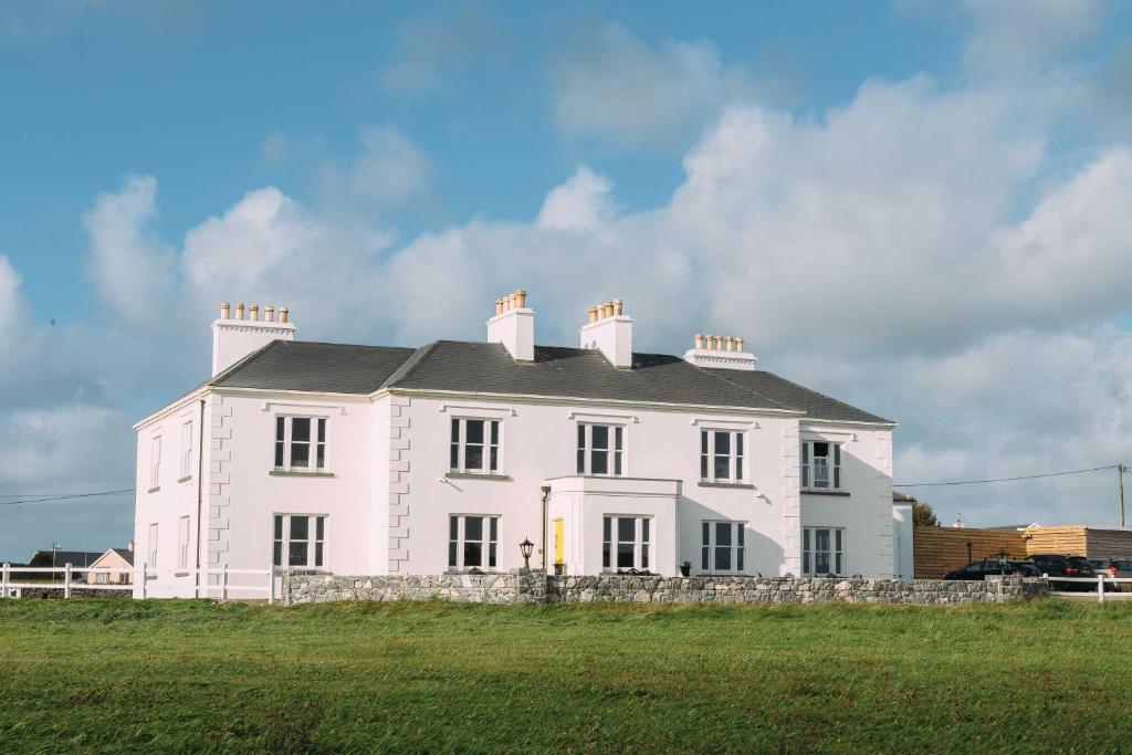 ein großes weißes Haus auf einem Feld in der Unterkunft Armada House in Spanish Point