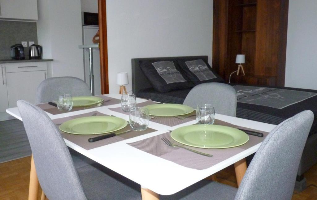 une table avec quatre chaises et des assiettes vertes dans l'établissement Appartement Perpignan Centre Place Catalogne, à Perpignan
