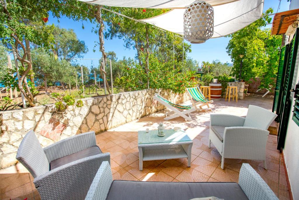 a patio with chairs and a table and a stone wall at Casa Bianca Rais Gerbi in Finale
