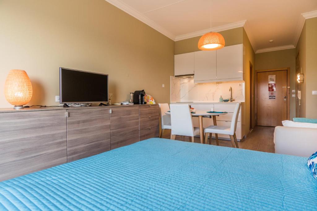 a bedroom with a blue bed and a kitchen at Beach House Ericeira in Ericeira