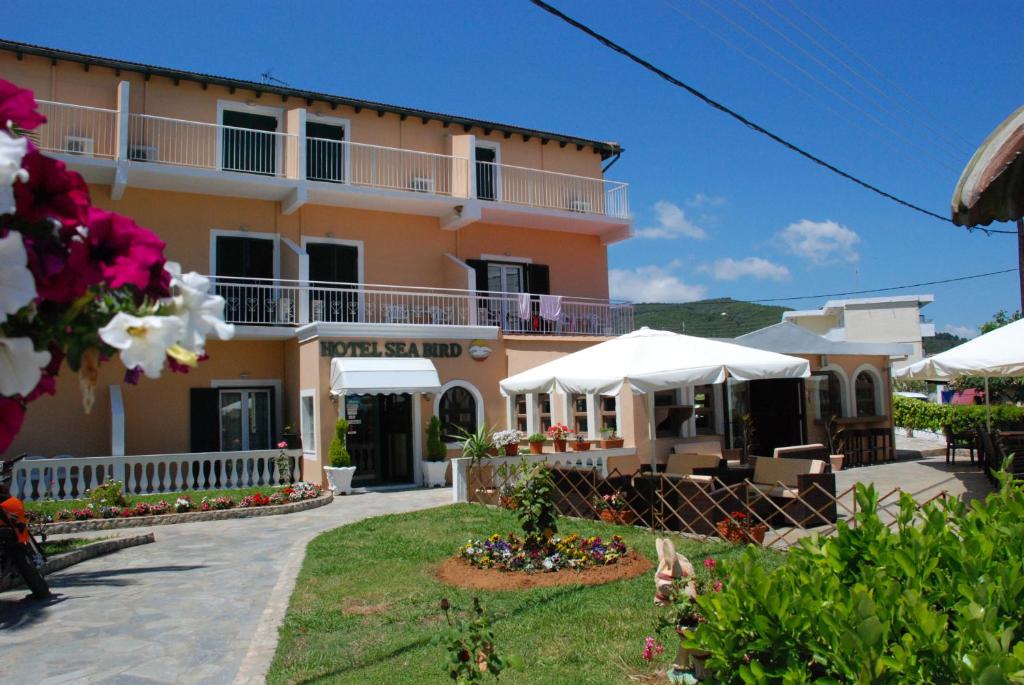 a large pink building with white umbrellas in front of it at SeaBird Hotel in Moraitika