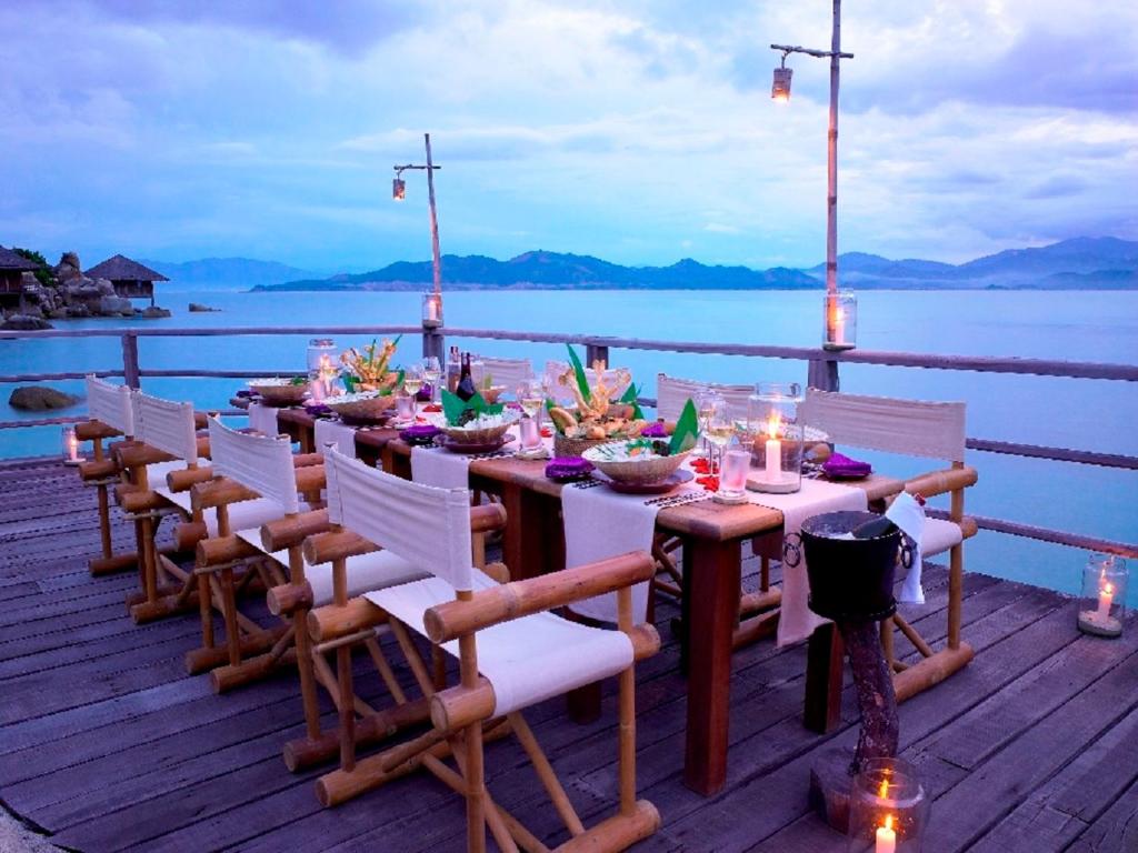 a dinner table on a deck with a view of the water at Six Senses Ninh Van Bay in Ninh Van Bay