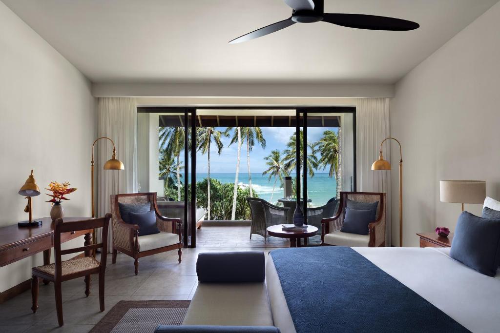 a bedroom with a bed and a desk and chairs at Anantara Peace Haven Tangalle Resort in Tangalle