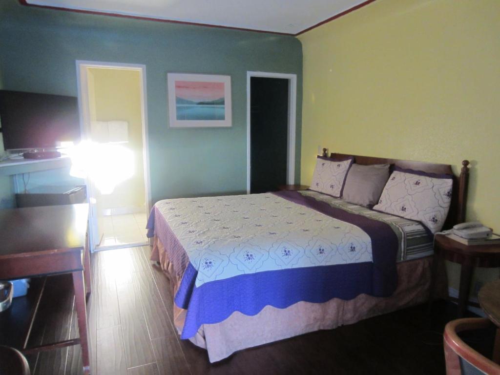 a bedroom with a bed and a table and a lamp at Travel Eagle Inn Motel in Long Beach