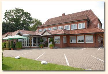 ein großes Haus mit einem Parkplatz davor in der Unterkunft Land-gut-Hotel Restaurant Kreuz Meyer in Stuhr