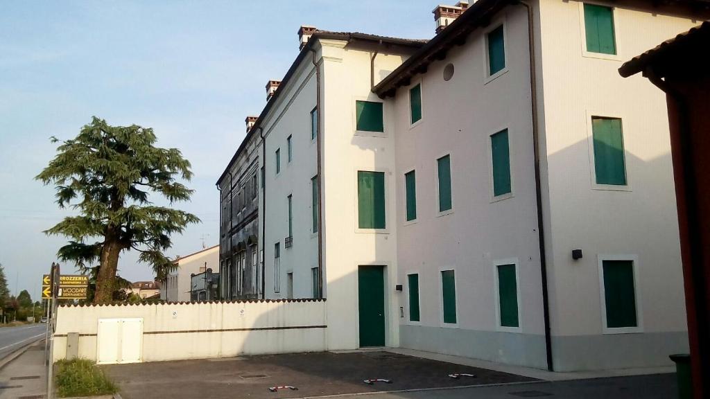 a white building with green windows on a street at Residence Montegrappa in Sandrigo