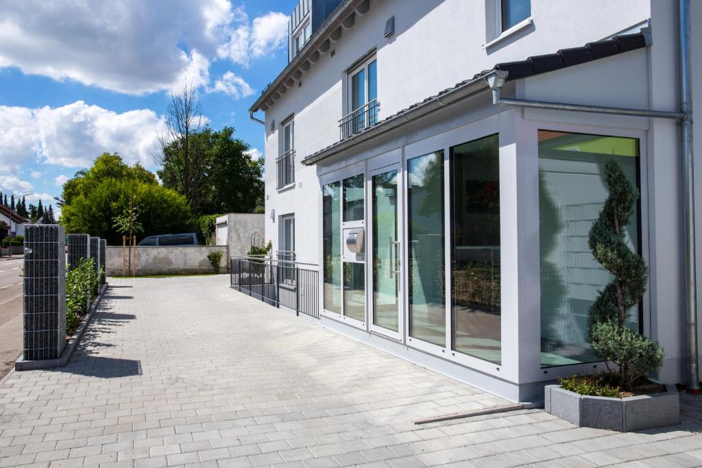 a white building with glass windows on a sidewalk at Pension Sonntag Ferienwohnungen in Ingolstadt