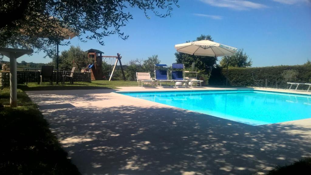 una piscina con sombrilla y un parque infantil en Al Cappellino, en Sona