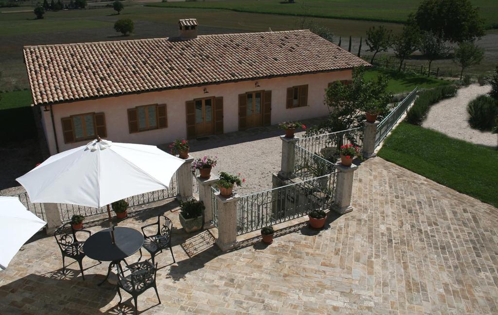 a patio with a table and an umbrella and a house at Agriturismo La Cascina di Opaco in Norcia
