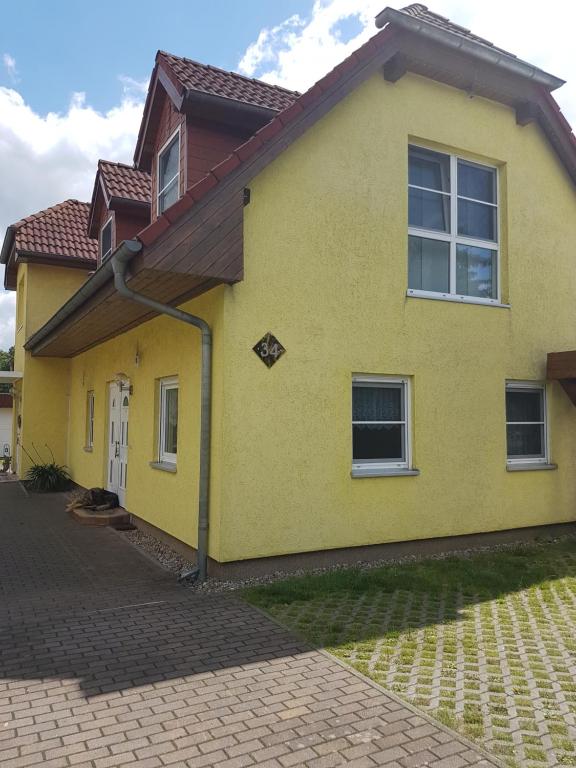 een geel huis met een bruin dak bij Ferienwohnung Regina in Müllrose