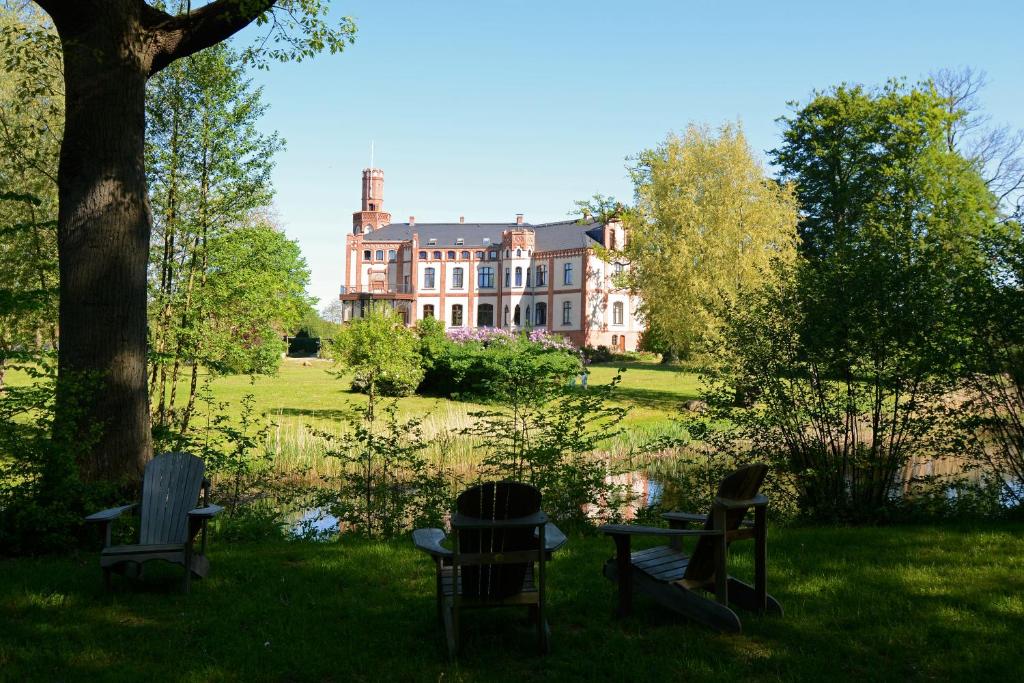 ヴィスマールにあるHotel Schloss Gamehlの前方の芝生に椅子を置いた大家
