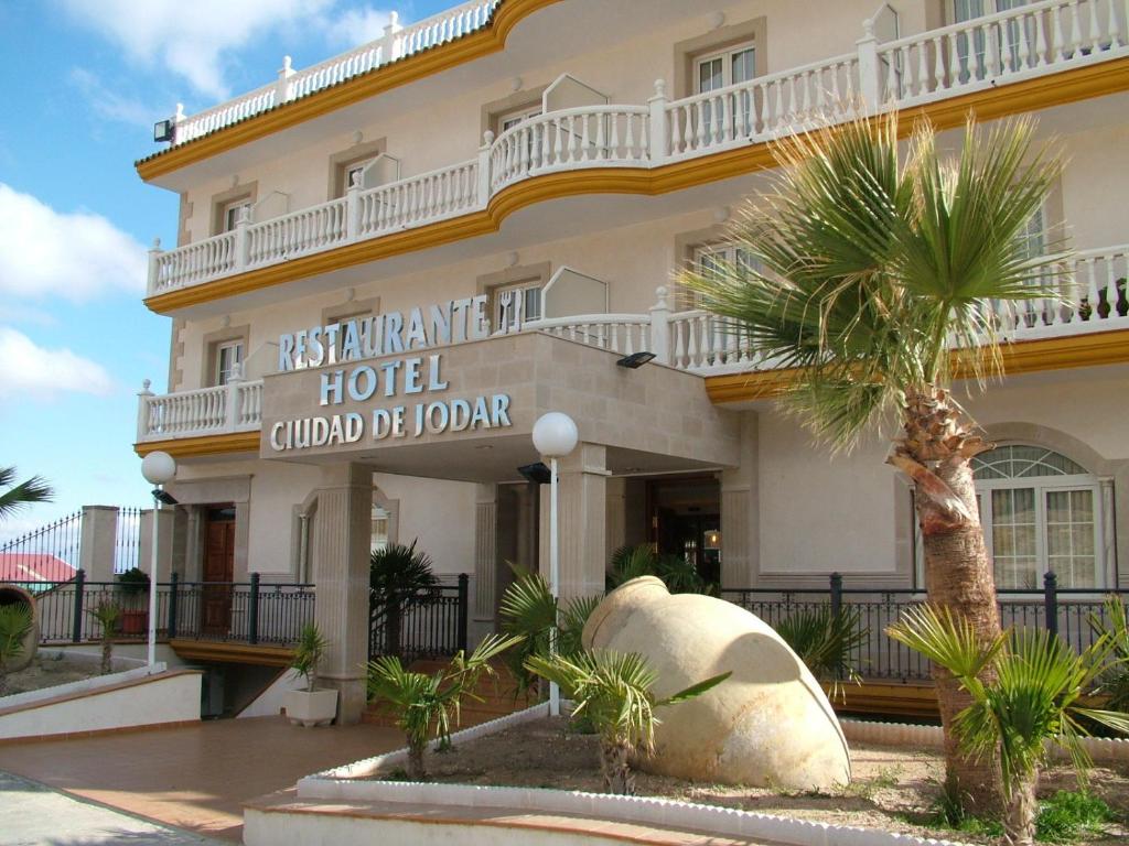 a hotel with a palm tree in front of it at Hotel Ciudad de Jódar in Jódar