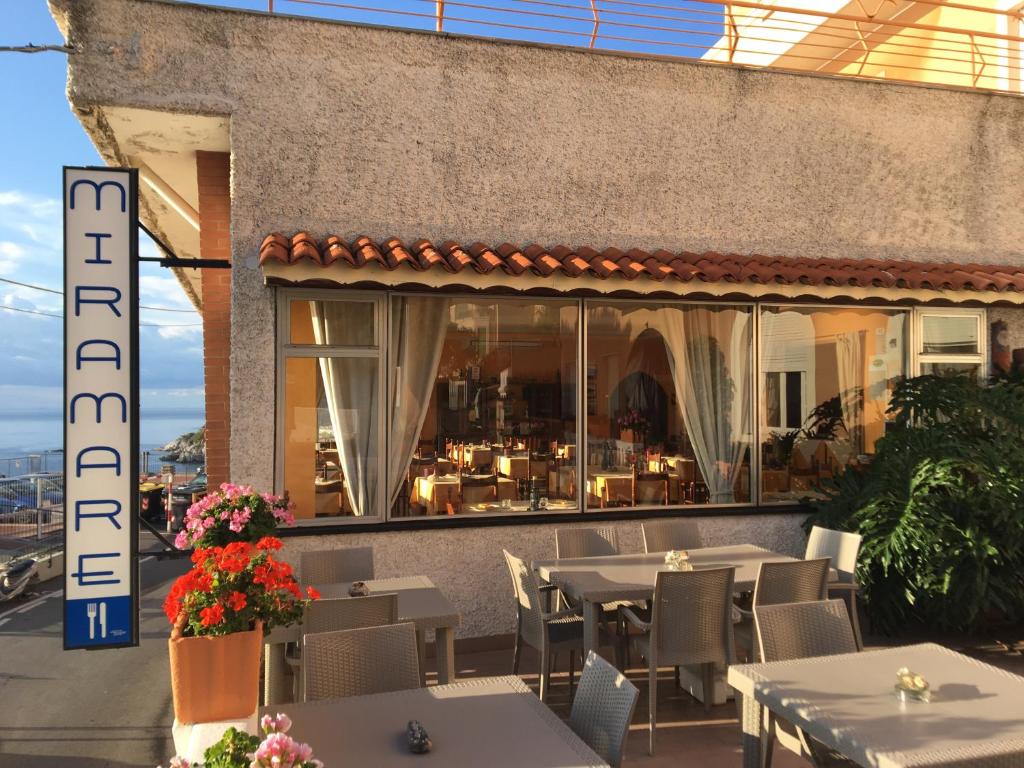 ein Restaurant mit Tischen und Stühlen vor einem Fenster in der Unterkunft Albergo Miramare in Bergeggi