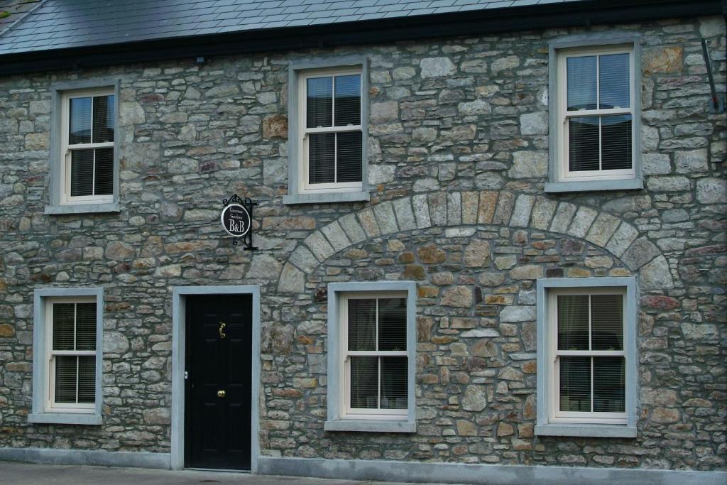 a stone building with white windows and a black door at Cornerstone 2 Bed Townhouse in Newtown-Dillon