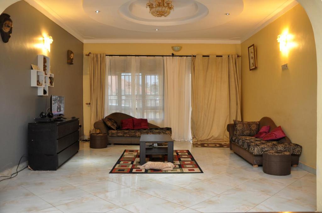 Sala de estar con 2 sofás y mesa en Namugongo Holiday Home, en Kasiyirize