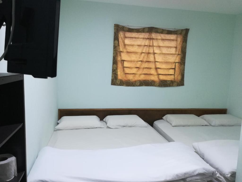 a room with three beds and a window at Axis Hotel in Taiping