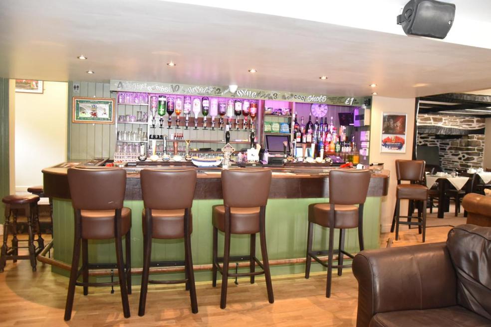 a bar in a restaurant with brown chairs at The Red Lion in Cardigan