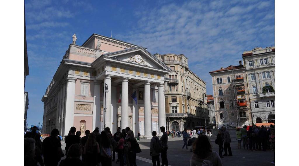 un groupe de personnes debout devant un bâtiment dans l'établissement UNICA nel cuore storico di Trieste, à Trieste