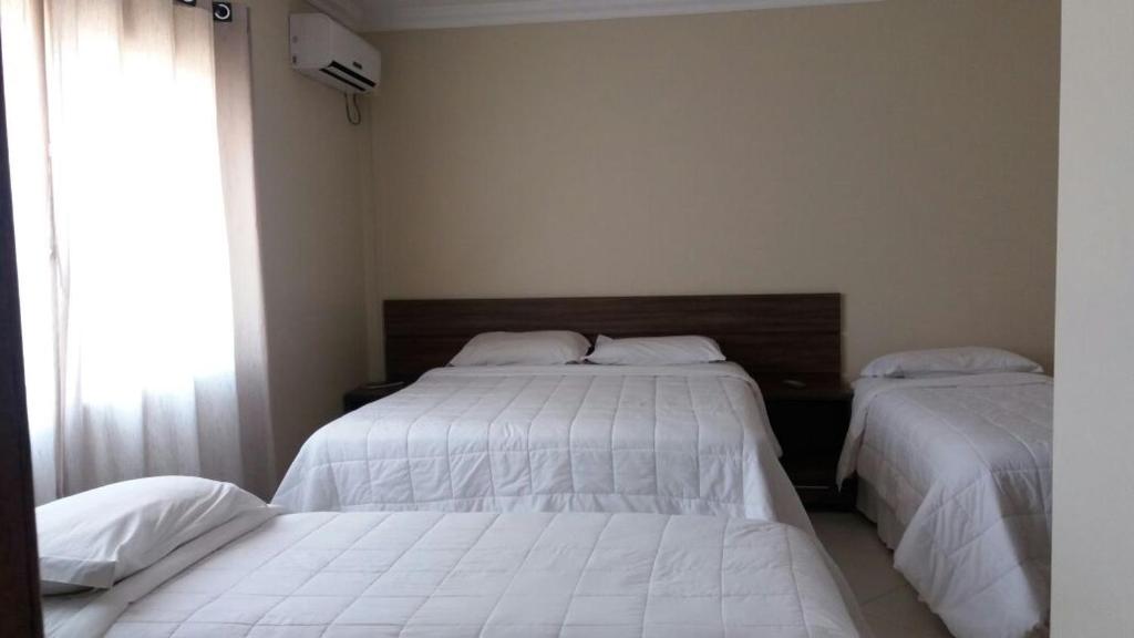 1 dormitorio con 2 camas y ventana en Imbau Palace Hotel, en Imbau