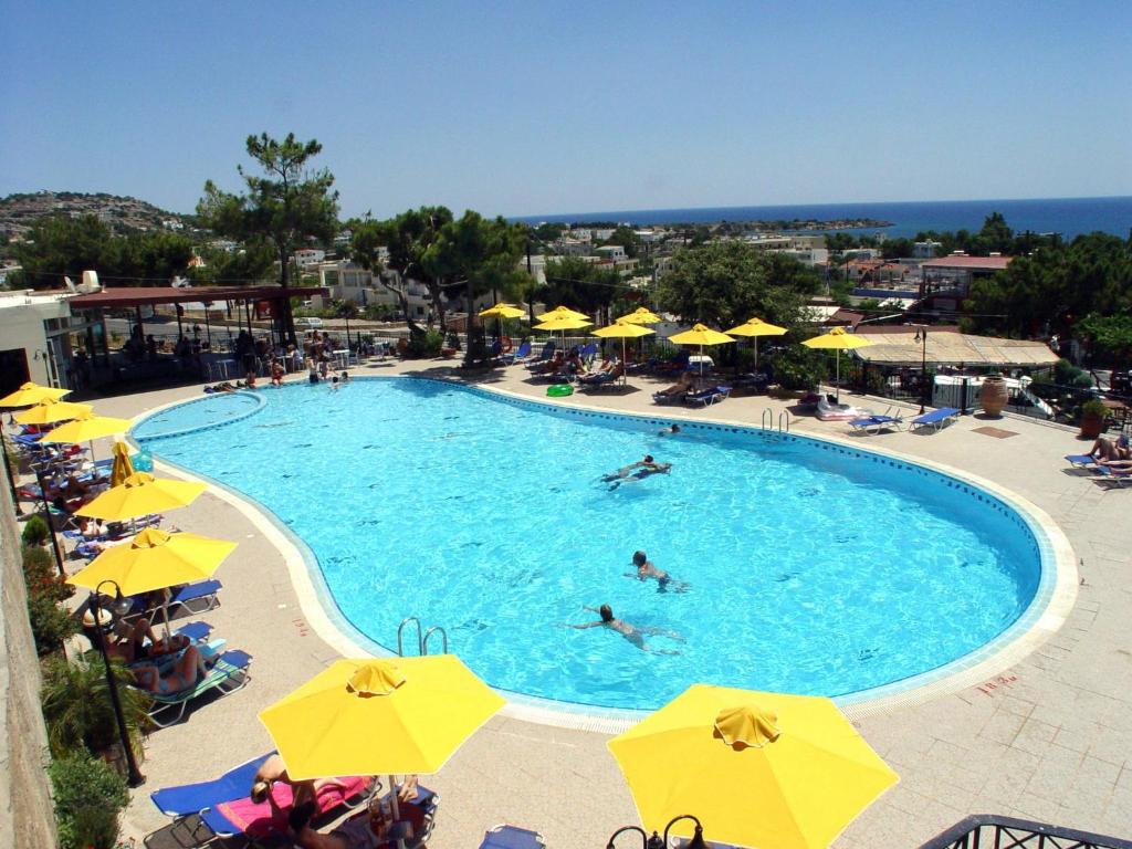 a pool with people swimming in it with yellow umbrellas at Marianthi Studios & Apartments in Pefki Rhodes
