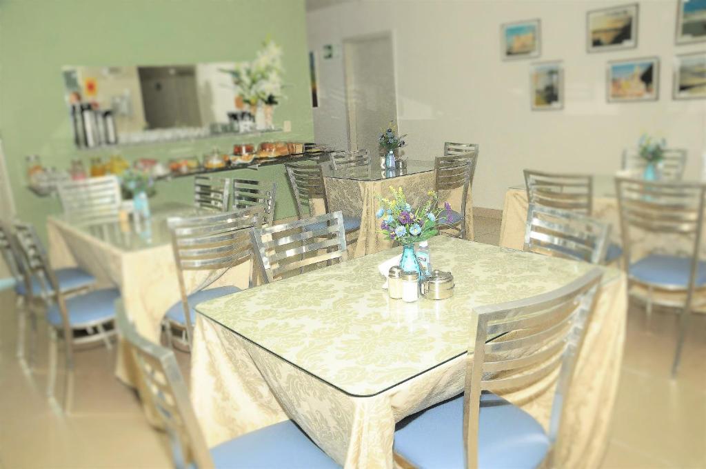uma sala de jantar com uma mesa e cadeiras com flores em Hotel Pousada Universitária em Teresina