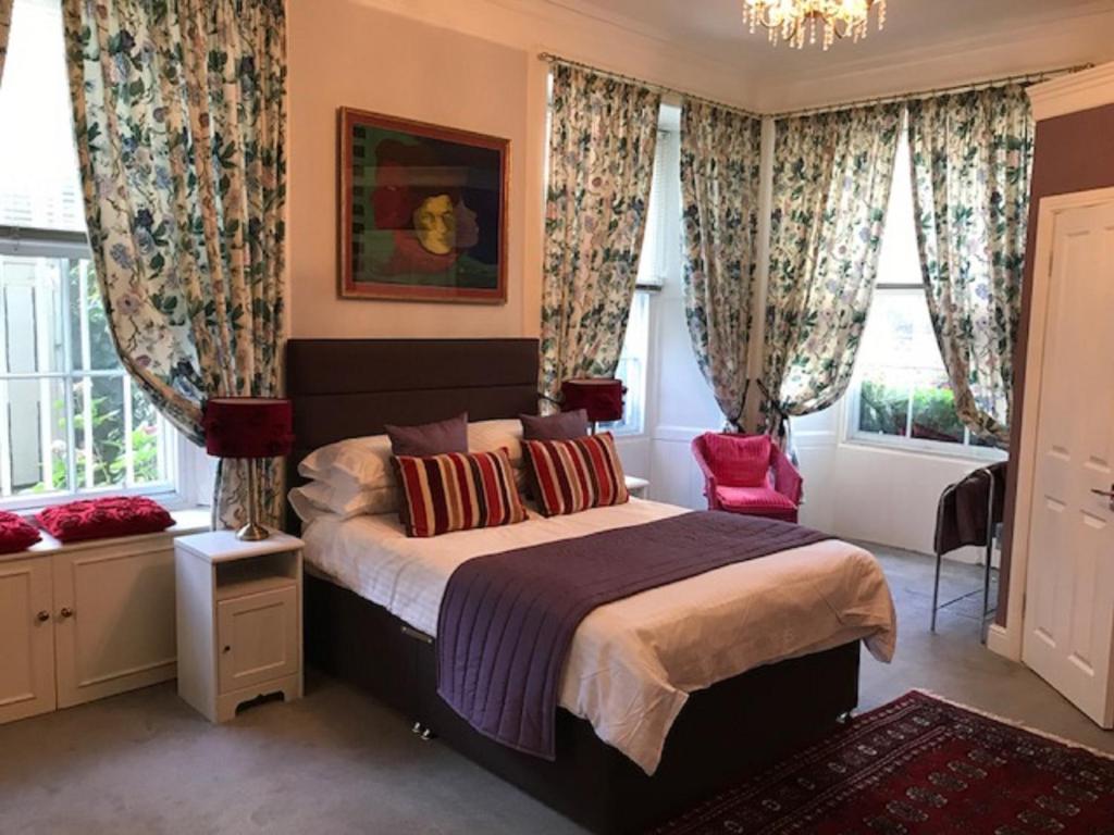 a bedroom with a bed with curtains and a red chair at 22 Chester Street in Edinburgh