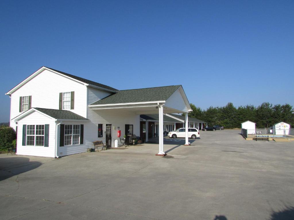 a white building with a car parked in a parking lot at Douglas Inn & Suites, Blue Ridge, GA in Blue Ridge