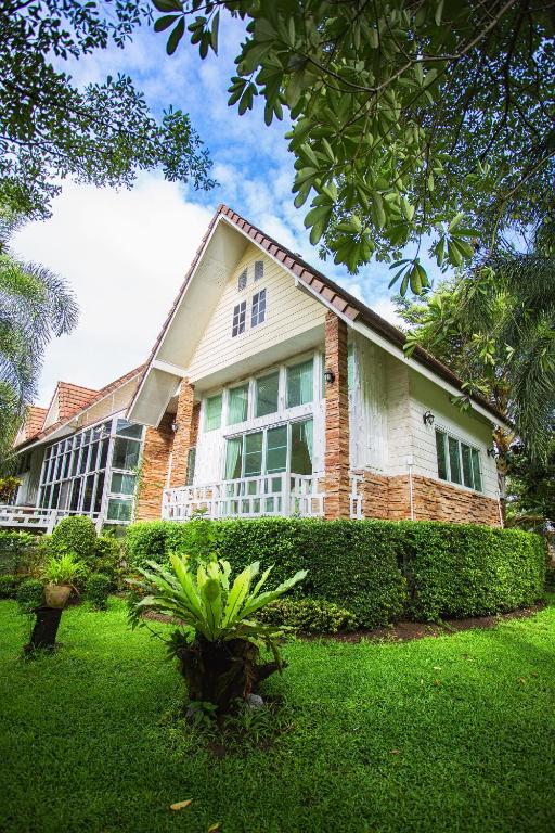 a house with a green yard in front of it at Watermill Resort in Nong Nam Daeng