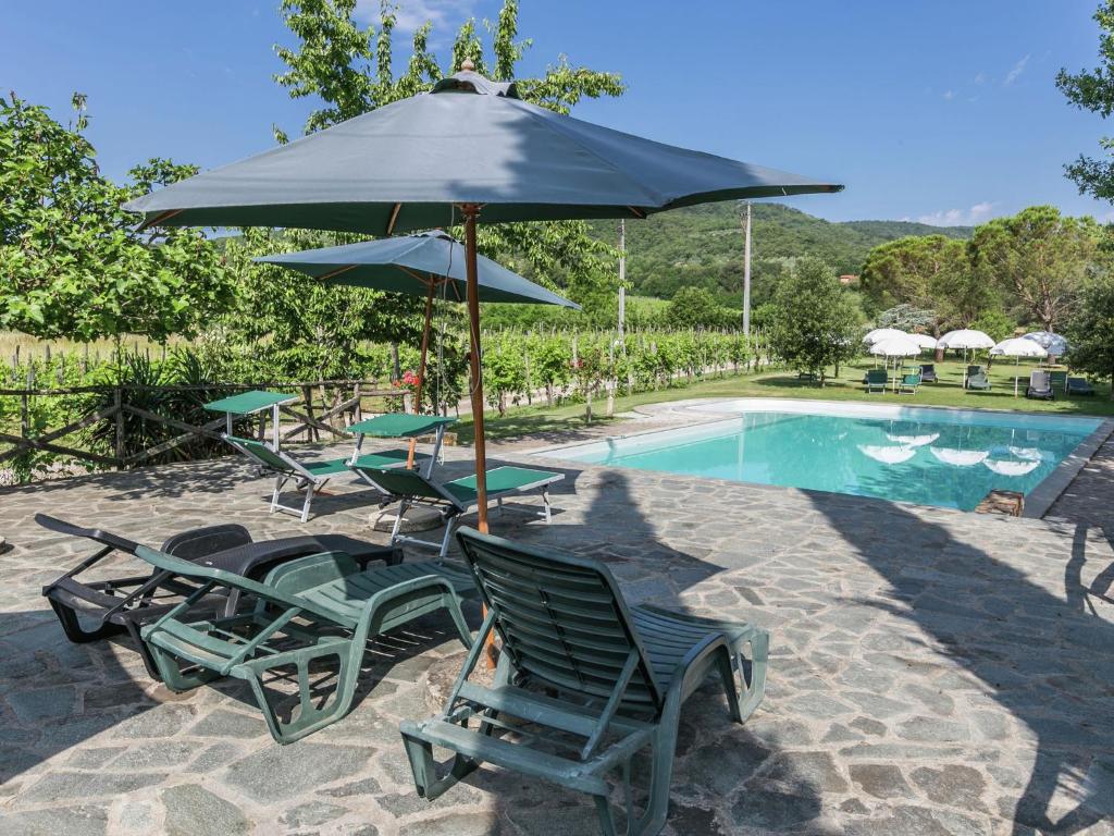 a group of chairs and an umbrella next to a pool at Authentic farm holiday with swimming pool pizza oven spacious garden and private terrace in Pietraviva