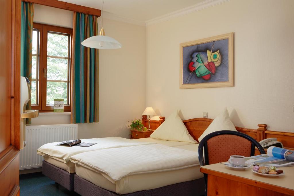 a hotel room with a bed and a table and a window at Logis Hotel-Restaurant Petry in Vianden