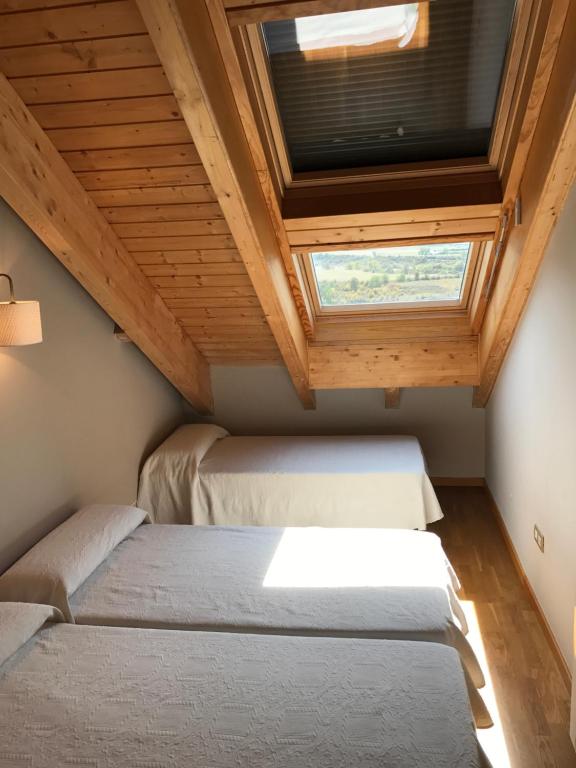 2 Betten in einem kleinen Zimmer mit Fenster in der Unterkunft Ático Balcon De Jaca II in Jaca