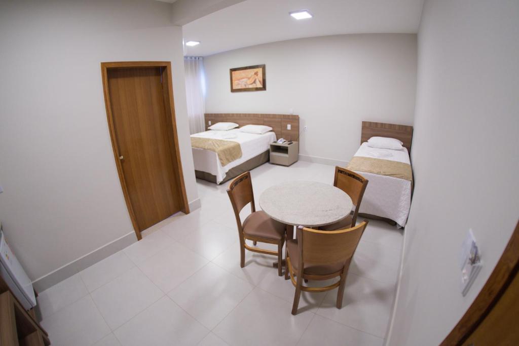 a room with two beds and a table and chairs at Hotel Royal in Salinas