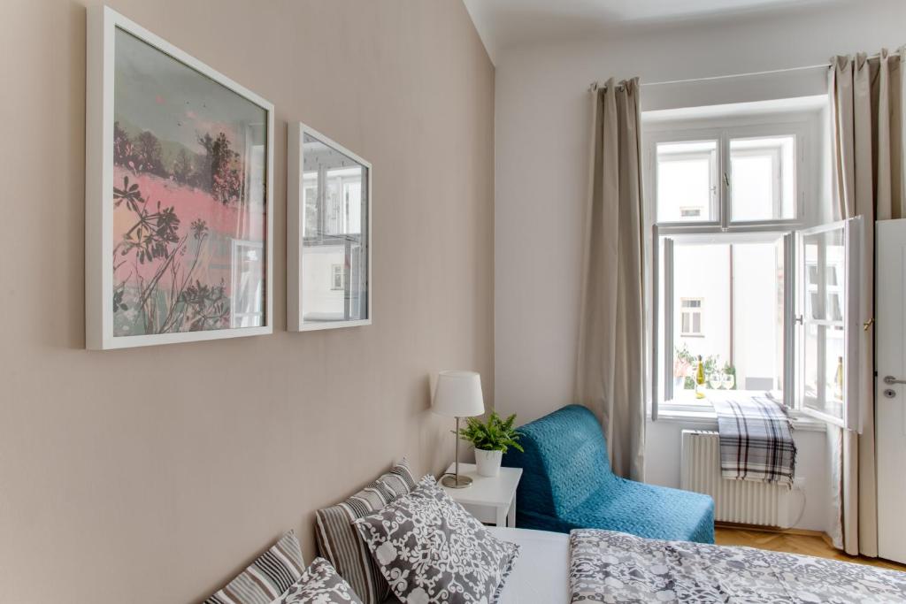 プラハにあるJT's Apartments Jecna str.のベッドルーム1室(ベッド1台、青い椅子、窓付)