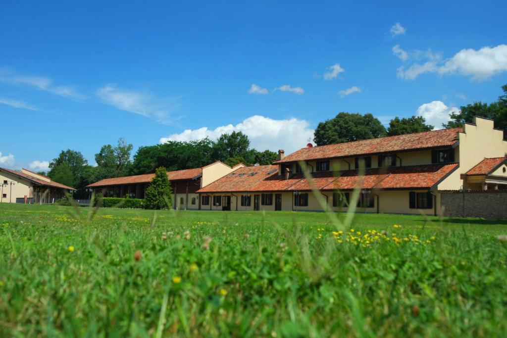 a building with a grass field in front of it at Country Hotel Castelbarco in Vaprio dʼAdda