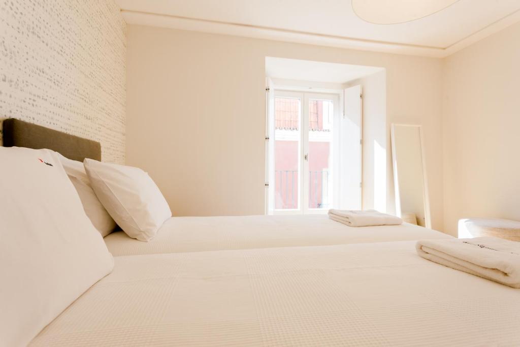 - une chambre blanche avec 2 lits et une fenêtre dans l'établissement FLH Portas do Sol Cozy Flat, à Lisbonne