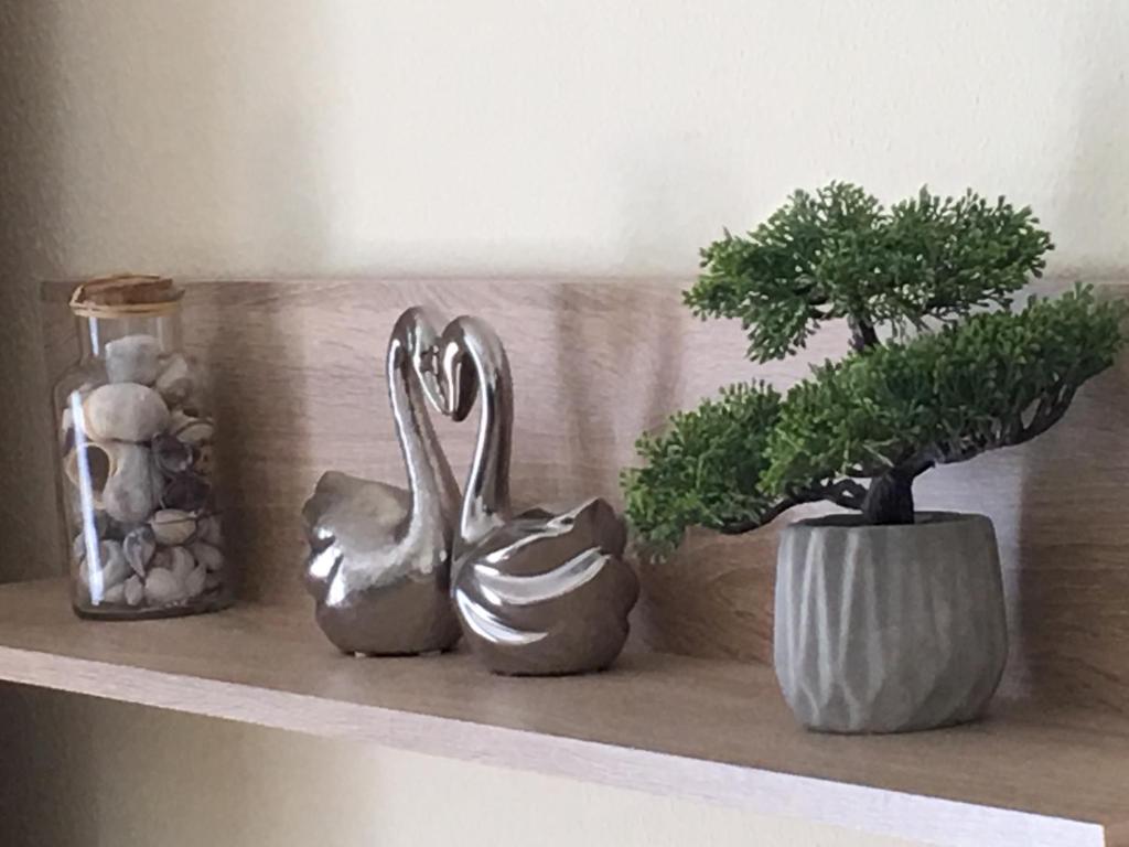 tres cisnes plateados sentados en un estante con una planta en A&H Apartment, en Oberhausen