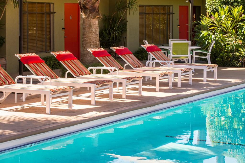 eine Gruppe von Stühlen neben einem Pool in der Unterkunft Desert Riviera Hotel in Palm Springs