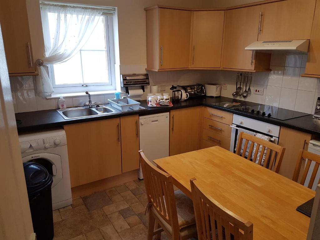 a kitchen with a table and a sink and a stove at Apartment 3, Pheonix Flats. in Portree