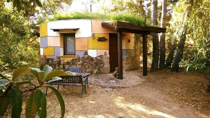 una pequeña casa con un banco delante en Apartamentos Rurales Ecopangea, en Valverde de la Vera