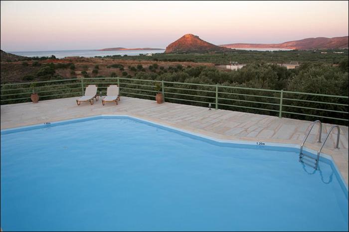 a swimming pool with two chairs and a view of a mountain at Liostasi Country Houses in Palekastron