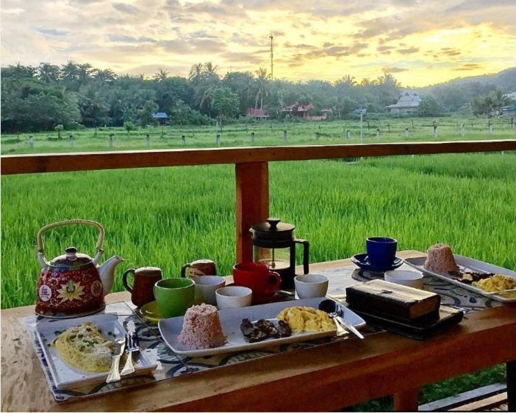 einen Tisch mit einem Teller mit Lebensmitteln mit Blick auf ein Feld in der Unterkunft Guerrera Rice Paddy Villas in Mambajao