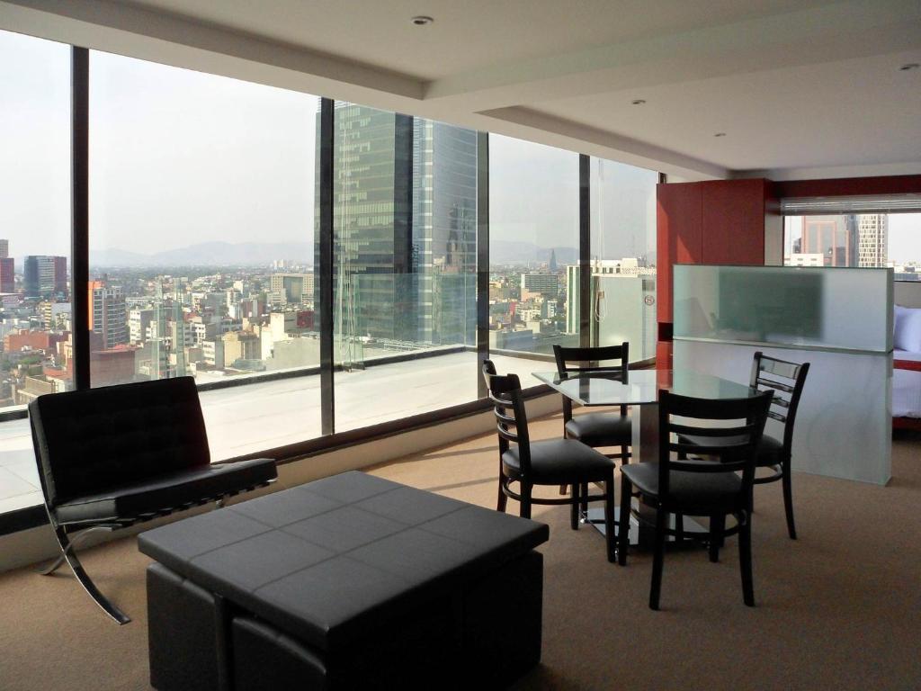 A bright suite living area with dining seating, lounge furniture and a broad city panorama.