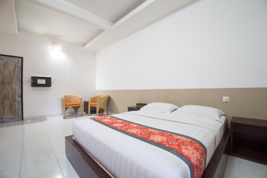 a bedroom with a large bed and chairs in it at Adikara Renon in Denpasar