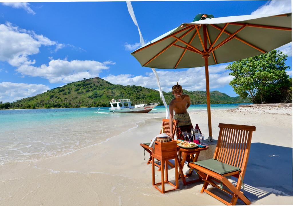 a man standing under an umbrella on a beach at Cocotinos Sekotong Lombok in Sekotong