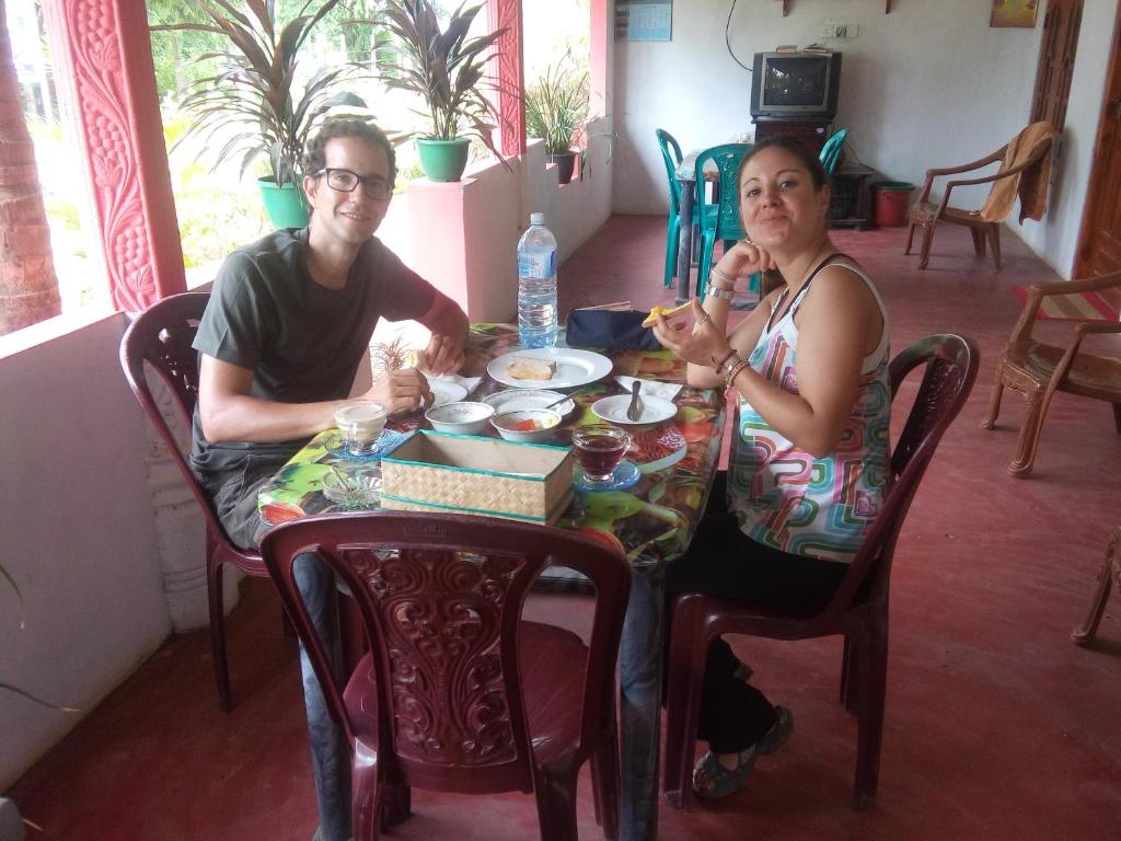 Um homem e uma mulher sentados à mesa a comer. em Pranu House em Nilaveli
