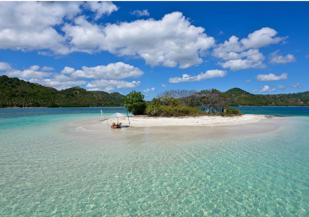 a small island with a boat in the water at Cocotinos Sekotong Lombok in Sekotong