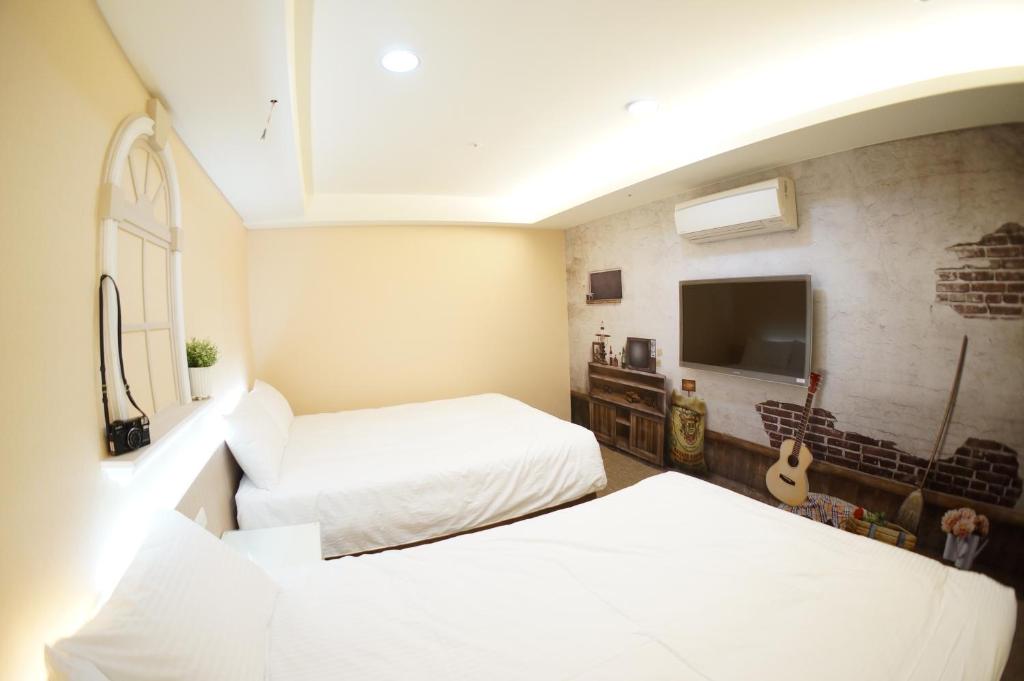 a bedroom with two beds and a tv in it at Morwing Hotel Fuzhong in Taipei