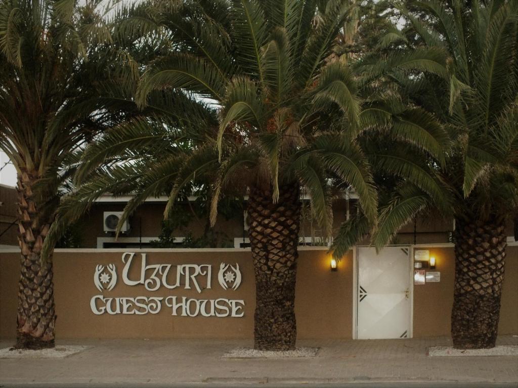 two palm trees in front of a guest house at Uzuri Guesthouse CC in Windhoek