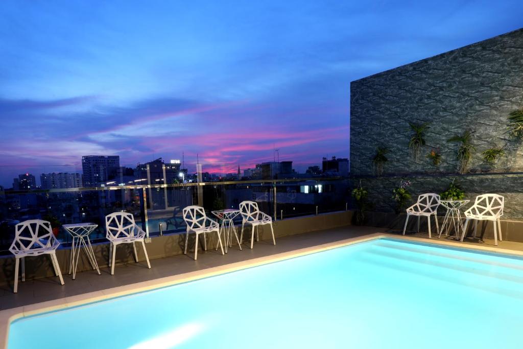 a rooftop patio with chairs and a swimming pool at night at Prague Hotel in Ho Chi Minh City