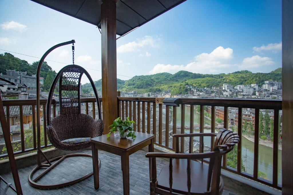 eine Veranda mit 2 Stühlen und einem Tisch auf dem Balkon in der Unterkunft Wang Jiang Reclusive Boutique Inn in Fenghuang